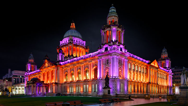 晚上的贝尔法斯特市政厅亮起紫色和橙色的灯光